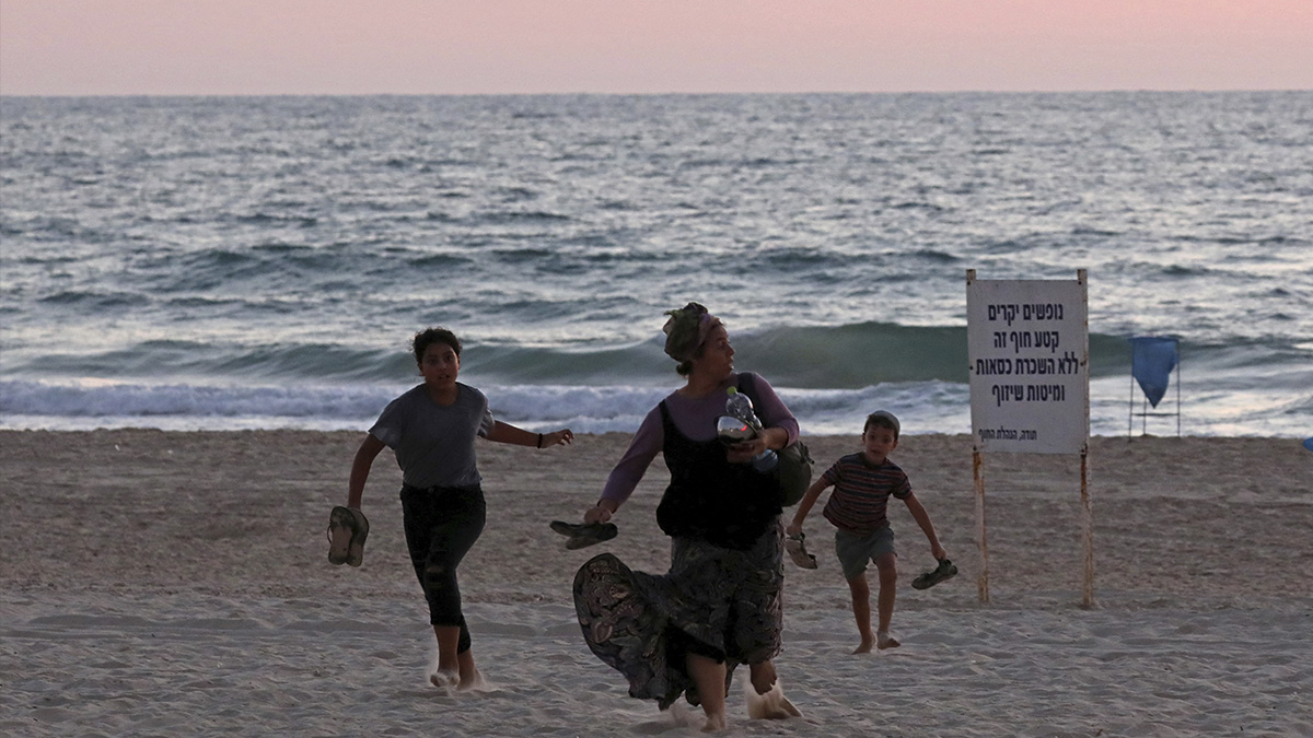 Huyen de playa en Tel Aviv, Israel, ante alerta de bombardeo