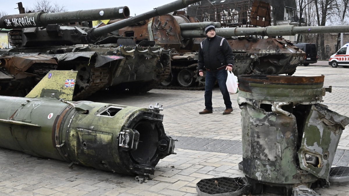 Ucrania Rusia invasión, hombre camina entre tanques rusos destruidos