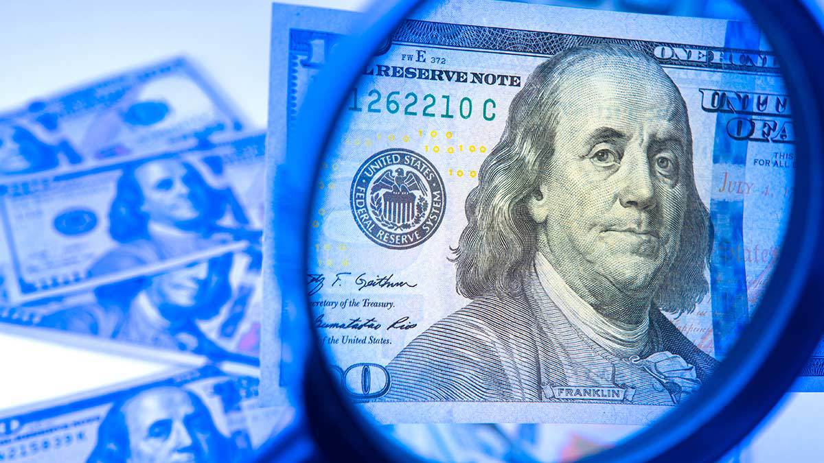 Identificar dólares falsos, billete de 100 bajo una lupa