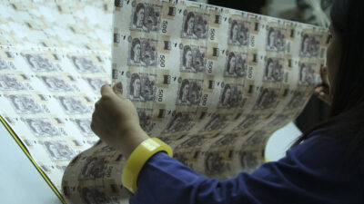 Materiales de los billetes; mujer revisando un pliego de billetes