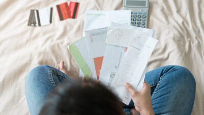 Errores en finanzas personales según Condusef, mujer sentada leyendo facturas