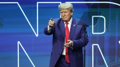 Expresidente de Estados Unidos vestido con un traje azul y corbata roja en un acto de campaña