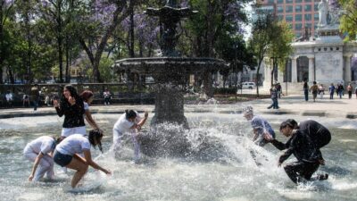 Gente aventándose agua en una fuente de la Alameda Central