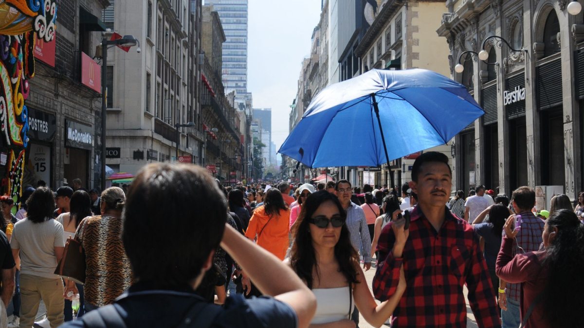 Personas se protegen del sol en la calle de Madero del Centro Histórico de la CDMX.