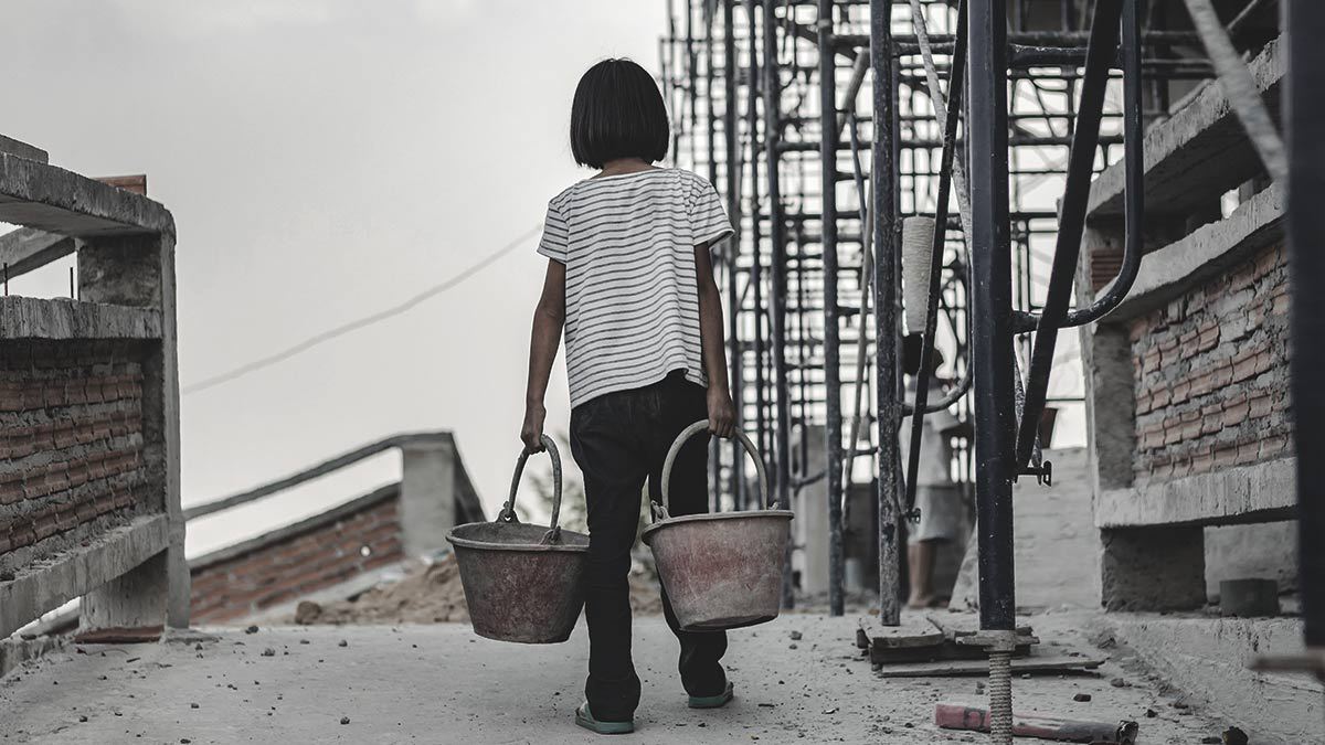 Trabajo Infantil: Niña cargando dos cubetas metálicas para cascajo en una construcción
